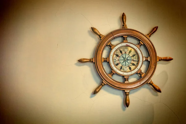 Concept: travel, sea navigation. Ship's nautical steering wheel and old compass on a light background with copy space.