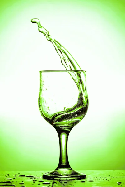 在杯子里溅起的酒 绿色阴影背景 — 图库照片