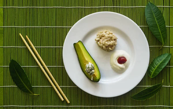 Healthy breakfast with avocado in a restaurant, Japanese serving with tropical leaves. Bamboo mat, chopsticks
