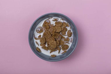 Minimalizm. Sağlıklı kahvaltı. Gri kâse Mısır gevreği süt veya yoğurt üzerinde pembe bir arka plan ile. Konsept: menü, diyet, kilo