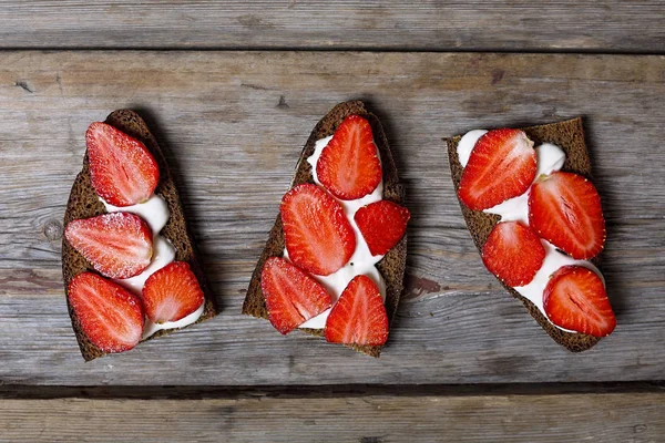 Healthy food. sandwiches with cream and strawberries on a wooden background.