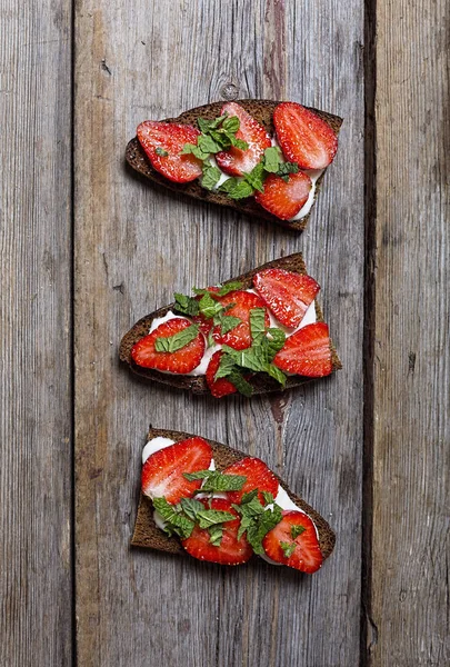 Healthy food. sandwiches with cream and strawberries on a wooden background.