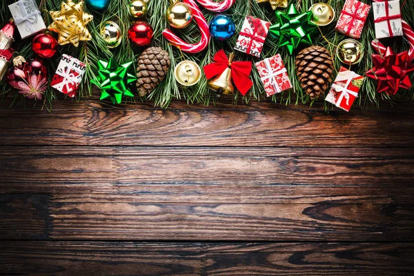 Vánoční pozadí s jedlí a dekorace na tmavé dřevěné desce — Stock fotografie