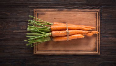 Tahta arka planda bir avuç genç havuç.