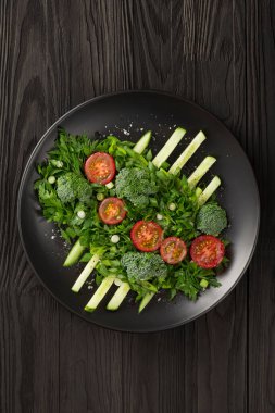 Sebze salatası ve siyah tabakta haute mutfağı. Fotoğraf gösterişsiz..