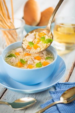 Sebzeli tavuk çorbası. Yemek masasında mavi bir kasede.