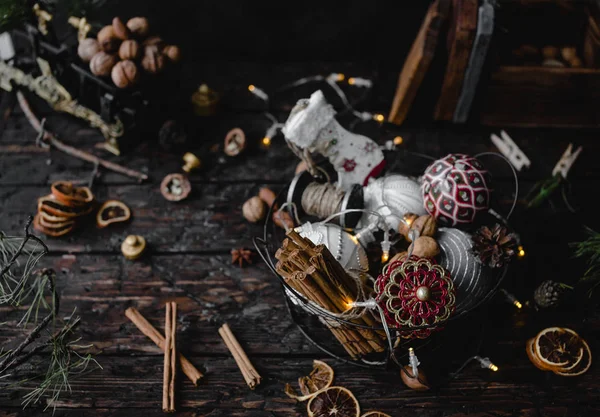 Yılbaşı süsleri ve koyu ahşap zemin üzerine metal sepet içinde tarçın soyulmuş kabuk yığını 