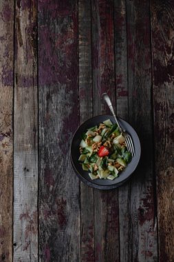 Eski ahşap arka plan üzerinde taze yaz salatası ile kavun, çilek, fındık ve fesleğen yaprakları