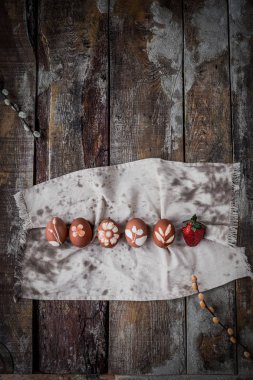 Ahşap arka plan üzerinde pamuk havlu üzerinde doğal süsler ile Paskalya yumurtaları satır