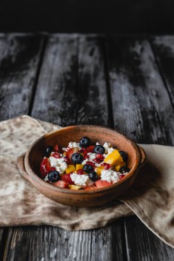 Koyu ahşap arka planda rustik kil plakasında taze çilek ile servis edilen süzme peynir