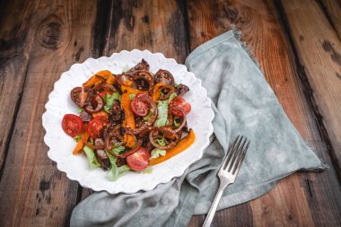 Izgara sebze, karamelize soğan ve ahşap masada kavrulmuş sığır eti ile Sıcak salata 