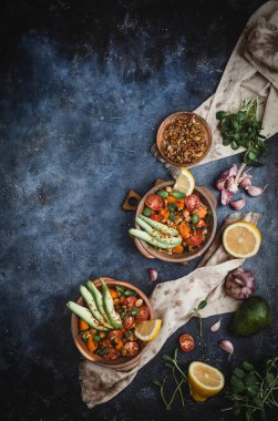 Taş arka planda kiraz domates, nohut, hurmaz, tohum ve avokado ile ev yapımı salata 