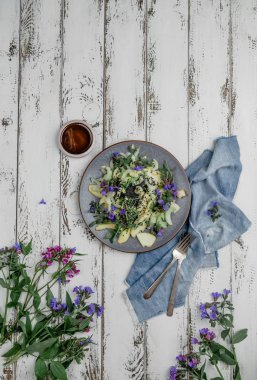 Eski beyaz ahşap arka plan üzerinde yenilebilir çiçekler ile Taze yeşil bahar salatası 