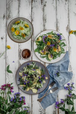 Eski beyaz ahşap arka plan üzerinde yenilebilir çiçekler ile Taze yeşil bahar salatası 