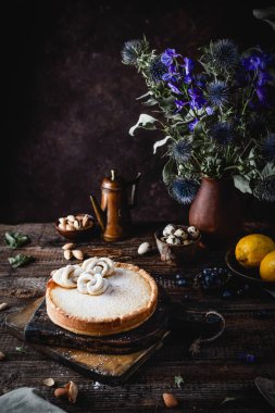 Kır çiçeği buketi ve olgun limon ile ahşap masada ev yapımı limon pasta  