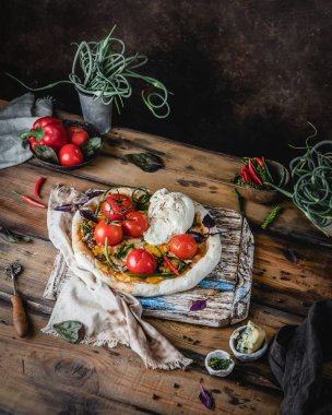 Ahşap masada dalak ve Burrata peynirinde pişmiş domates ile ev yapımı pizza 
