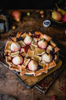 Ahşap masada bütün armut ve kırmızı frenk üzümü çilek ile taze pişmiş tatlı pasta