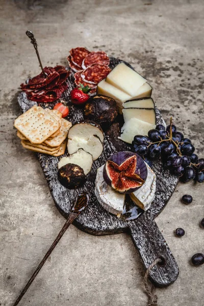 Peynir çeşitleri incirli, üzümlü, jambonlu ve krakerli eski püskü arka plan, üst manzara