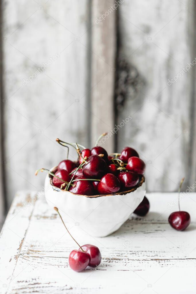 white bowl with sweet cherries on wooden table, close view 