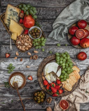 Tabaklar peynirle, çilekler üzümle, kırmızı portakallar da grunge arka planda.