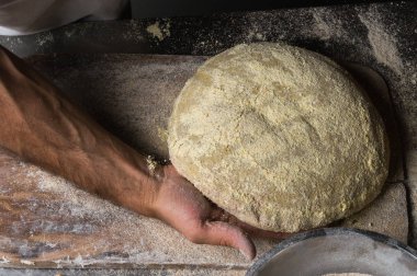 Male hands kneading dough on sprinkled with flour table, closeup clipart