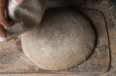 Fırıncı ekmek pişiriyor. Adam hamura un döker. Ekmek yapan adam