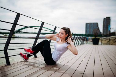 Uygun kız açık havada bisiklet crunch egzersiz yaparak.