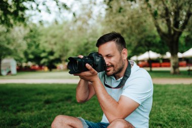 Çimenlerin üzerinde oturan fotoğrafçı fotoğraf çekme.
