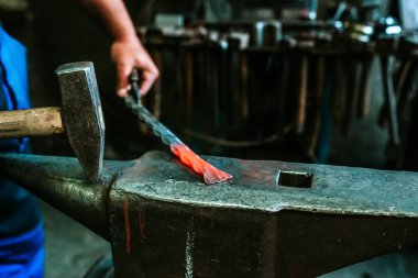 Yakın çekim yansıma demirci bir atölyede bir çekiç ve bir kırmızı-sıcak demir ile çalışır.