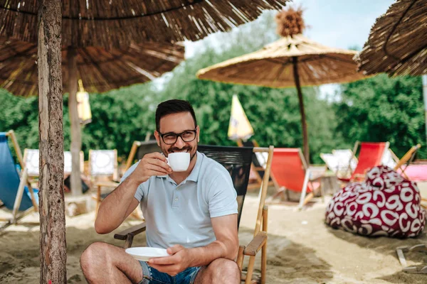 Portrait Smiling Young Man Drinking Coffee While Sitting Beach Chair Royalty Free Stock Photos