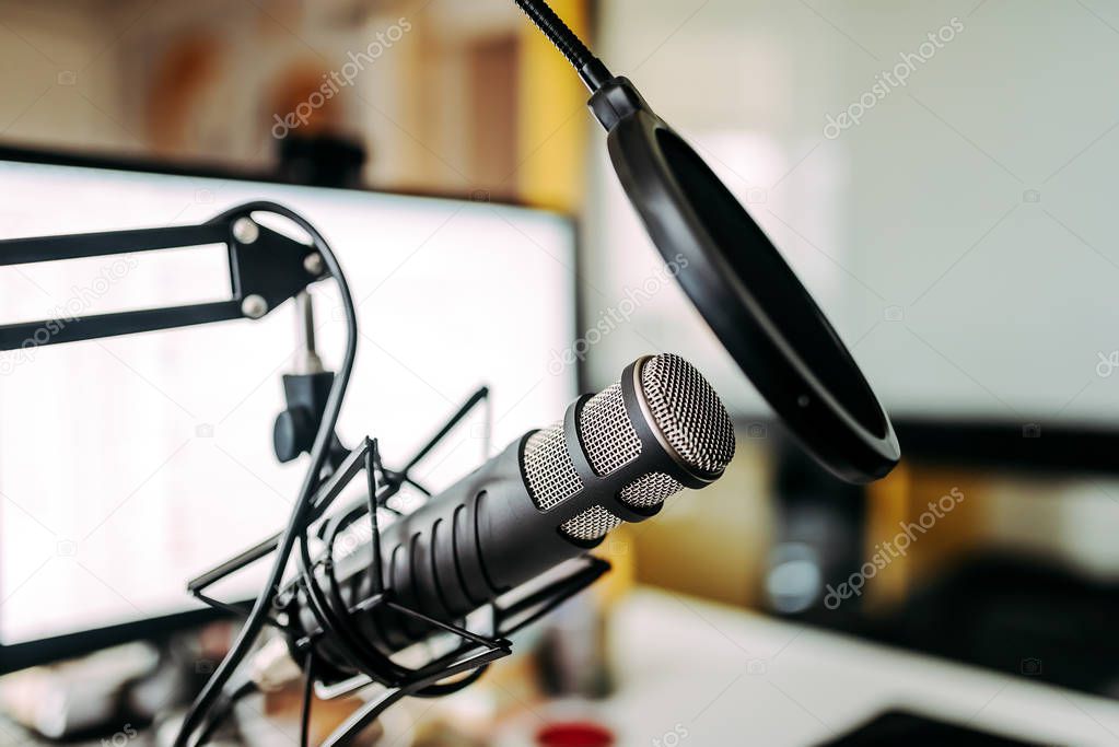 Close-up image of microphone and white computer screen in the background.