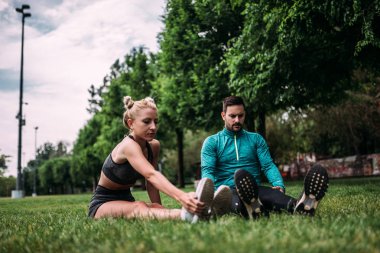 İki sporcu eğitim önce ısınma. Çimenlerin üzerinde otururken germe egzersiz yaparak.