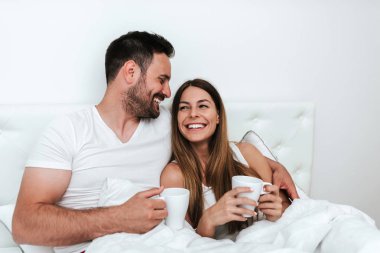 Çift içme kahve yatakta gülüyor.
