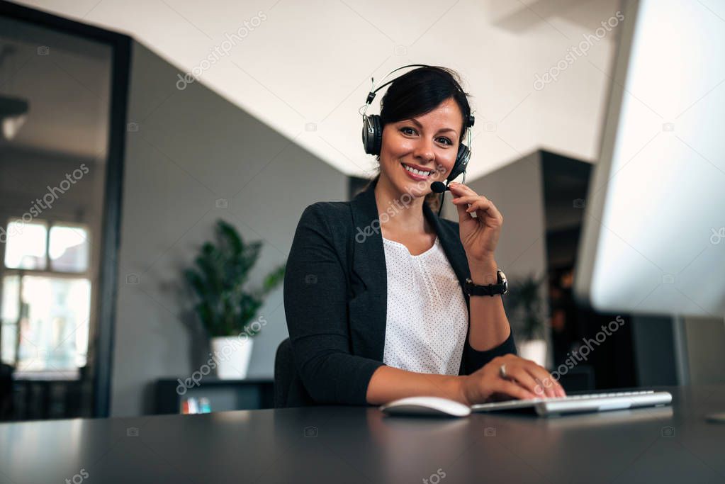 Portrait of happy female customer support operator at workplace.
