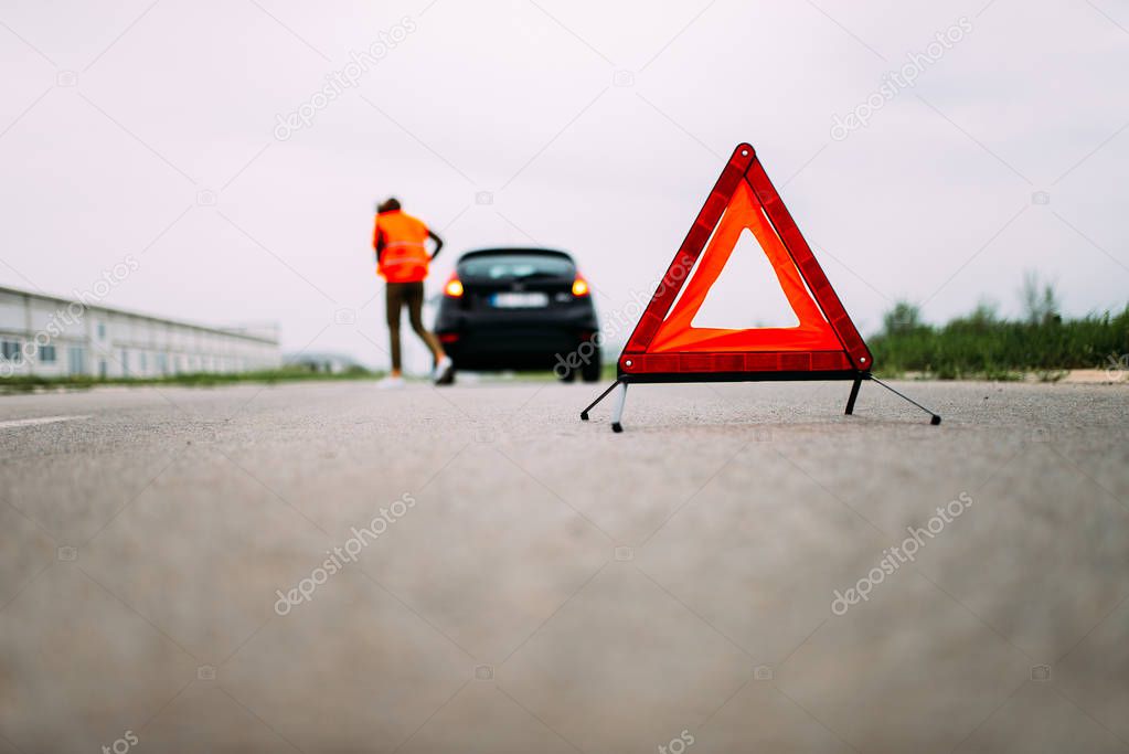 Broken car on road. Red warning triangle.