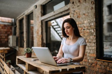 Dizüstü bilgisayar kullanarak ve kulaklık giyen kadın blogger.