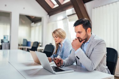 İş ortakları iki dizüstü bilgisayarlar kullanarak parlak bir ofiste çalışmak. 