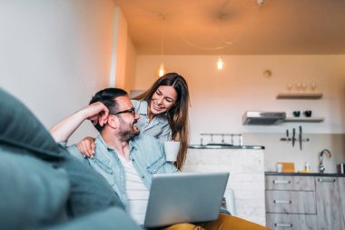 Çay içme ve daire dizüstü bilgisayar kullanarak bir çift. Yakın çekim.