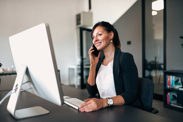 Бизнесмен звонит, сидя за компьютером в офисе
.