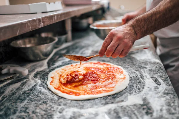 Przygotowanie Pizzy Ręka Szefa Dodając Sos Pomidorowy Ciasto Pizzy — Zdjęcie stockowe