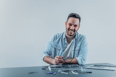 Gülümseyen mühendis dizüstü donanım sorun üzerinde çalışıyor. Kameraya bakarak.