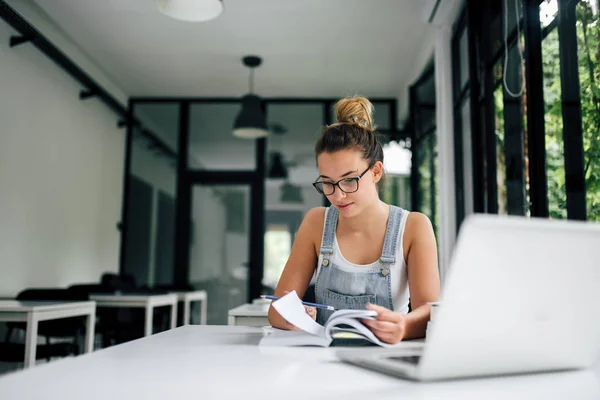 College girl studying from textbook.