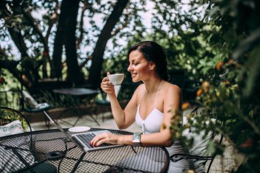 Dizüstü bilgisayar kullanarak ve Bahçe kafede kahve içme güzel kadın.
