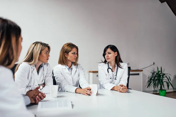 Serious female doctors discussing diagnosis while sitting at the table.