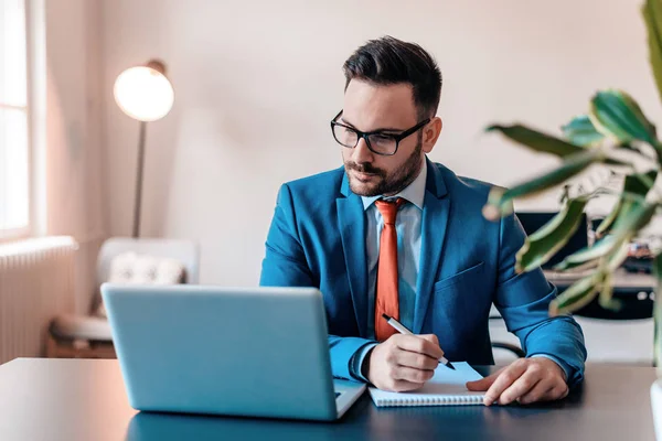 Schöner Geschäftsmann Mit Brille Macht Sich Notizen Während Laptop Arbeitet — Stockfoto