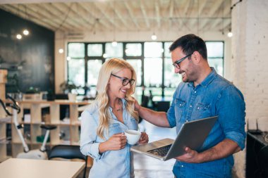 İki gülümseyen iş arkadaşlarınızla ayrılırlar. Eğleniyor, dizüstü bilgisayar kullanarak.