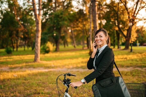 Mujer Negocios Sonriente Montando Una Bicicleta Parque Hablando Por Teléfono —  Fotos de Stock