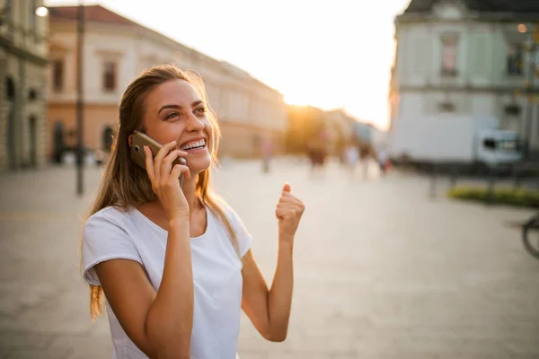 Excited student receiving a good news on mobile phone outdoors.