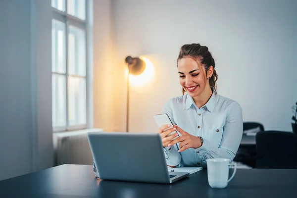 Imagem Jovem Mulher Feliz Olhando Para Telefone Enquanto Sentado Mesa — Fotografia de Stock