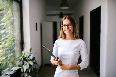 Kameraya bakarak ve gülümseyen genç iş kadını.